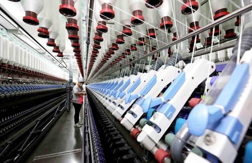 3月10日,山东省枣庄市市中区一家纺织企业的工人在车间生产纺纱产品.