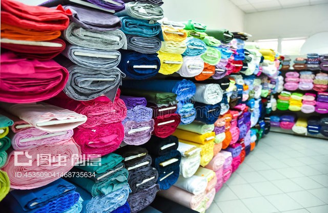 工厂里的布料和纺织品卷。Rolls of fabric and textiles in a factpory shop.